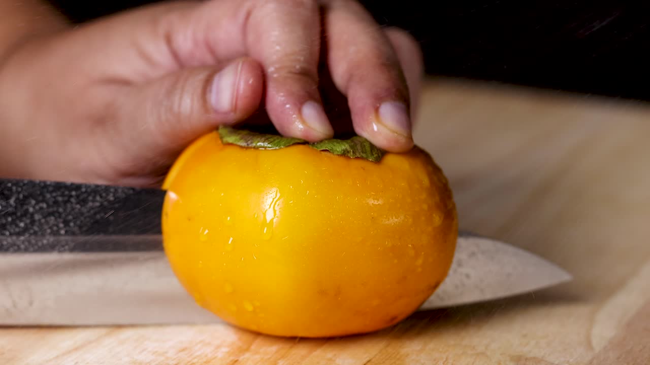 la mano corta cuidadosamente un caqui maduro en rebanadas