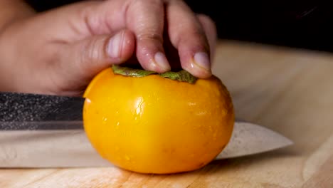 hand carefully slices a ripe persimmon