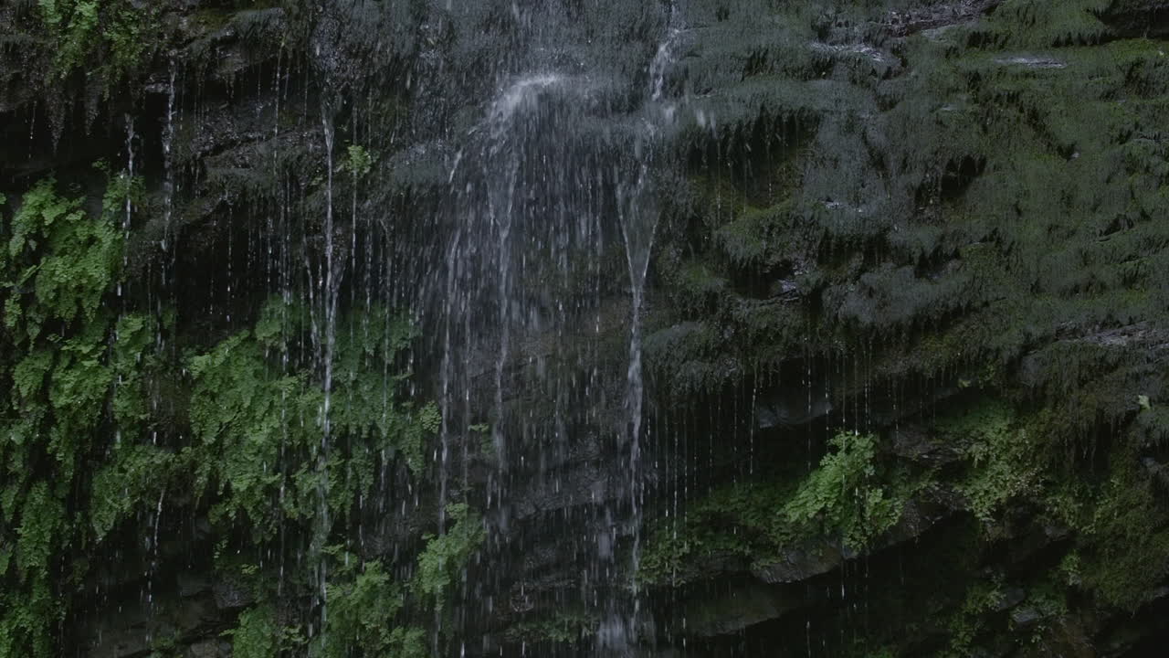 Waterfall cascading down mossy rock face