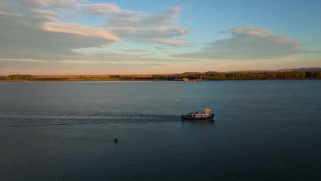 aerial shot pusher tug navigating a big river illuminated by sunlight, blue sky, 4k50fps