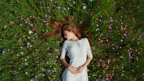 young woman lying peacefully in a field of wildflowers