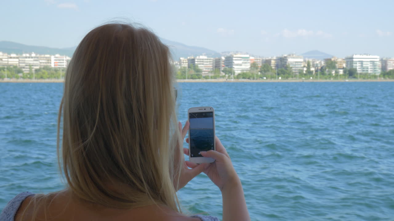 mujer en el barco tomando fotos del mar en el móvil
