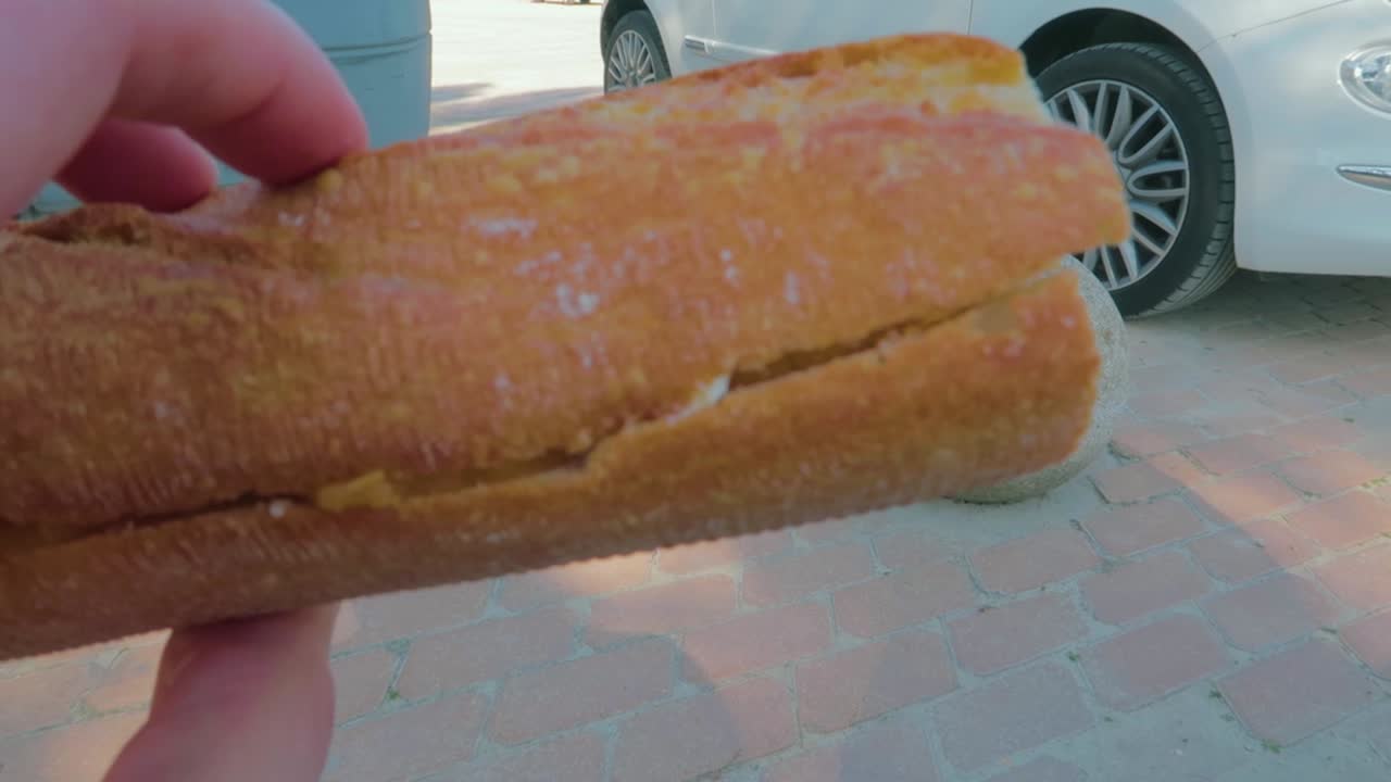 una vista de cerca de un pan en la mano de un hombre mientras está de pie al aire libre con su camión