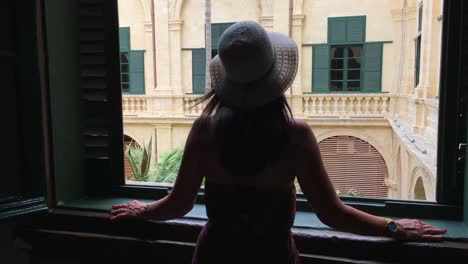 chica en la ventana con sombrero y vestido de verano, sol, luz y sombra