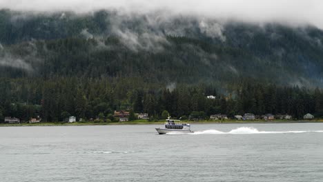 des montagnes brumeuses et un petit bateau naviguant sur le canal de gastineau, juneau, en alaska.