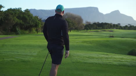 Golfista-Masculino-Observa-Cómo-Su-Tiro-Vuela-Por-El-Campo-De-Golf-Verde-Al-Amanecer