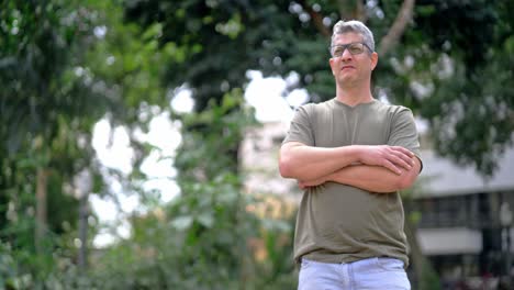 man standing with crossed arms in a park