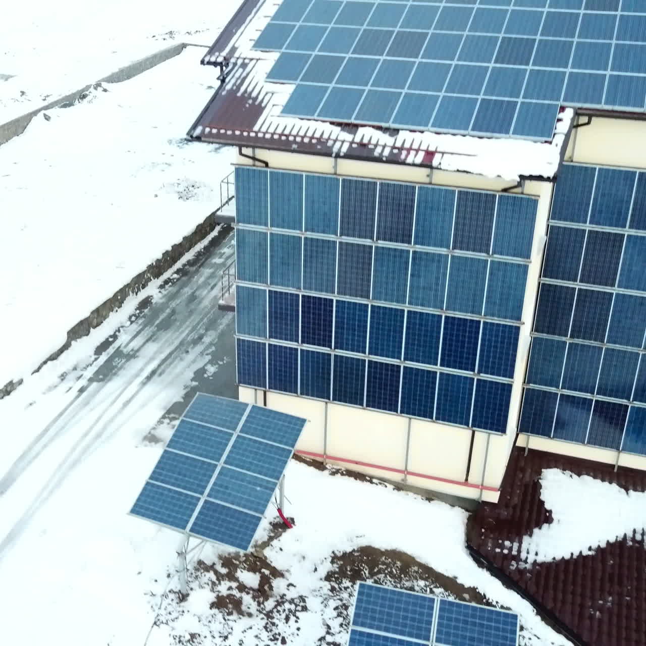 Hotel complex in the mountains with solar panels on the snow. Rows of snow covered solar panels in a small solar power plant.