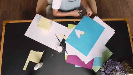 vue de dessus d'une fille coupant du carton en forme de coeur sur le bureau