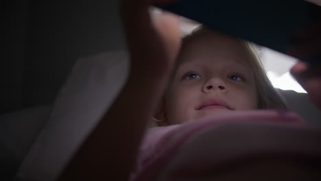 girl playing on phone in bed