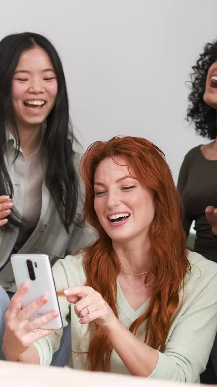 Amici diversi e allegri che usano lo smartphone a casa