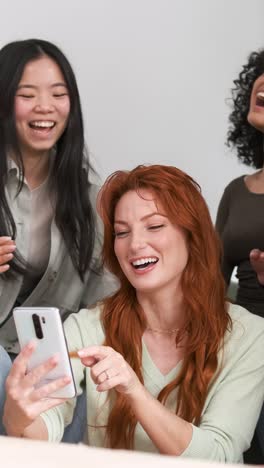 cheerful diverse friends using smartphone at home