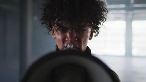 portrait of african american man talking in megaphone in empty parking garage in empty parking garag