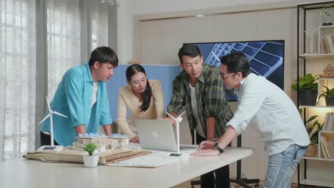 asian engineers group with the solar panel house model discuss about  work on a laptop at the office