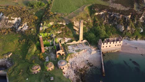 Porth-Wen-abandoned-coastal-derelict-brickworks-remains-golden-sunrise-countryside-bay-aerial-descending-birdseye-view