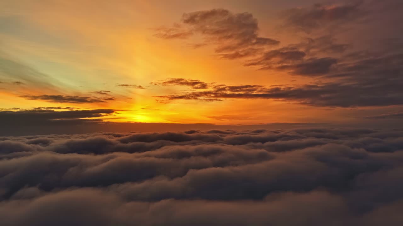 Distesa di nuvole rilassante dai toni caldi che si estende sotto l'orizzonte all'alba, mentre colori luminosi si allungano nel cielo