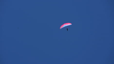 un paracaídas rosa y azul vuela solo en un cielo azul brillante sobre los alpes, suiza, engelberg