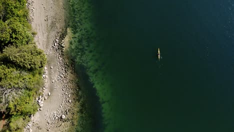 aerial view of kayaker leisurely paddling past rocky shore