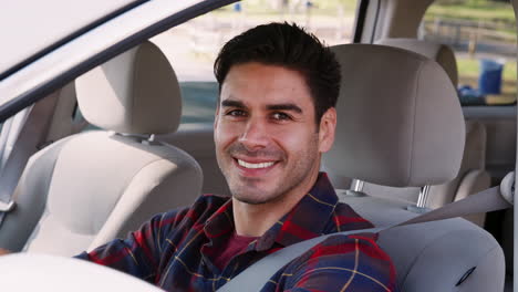 Young-man-in-car-driving-seat-looking-out-of-side-window