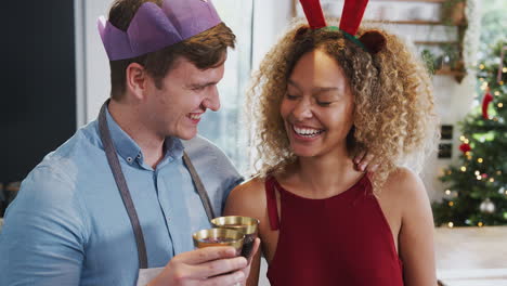 pareja con cuernos de vestido de lujo y sombrero de papel haciendo un brindis el día de navidad