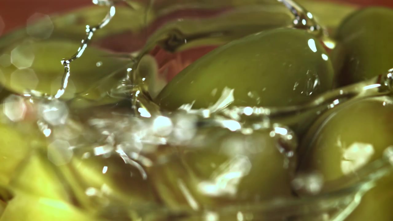Versamento di liquido al rallentatore su olive verdi