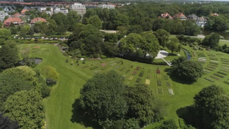 Drone-Slowmotion-of-a-Dutch-Flower-Garden-in-The-Hague-with-Tourists-and-Seagulls-passing,-during-Sunny-Weather