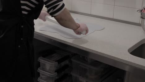 una persona desplegando una hoja fresca de glaseado para decorar galletas de mantequilla hechas a mano en una pastelería, 4k