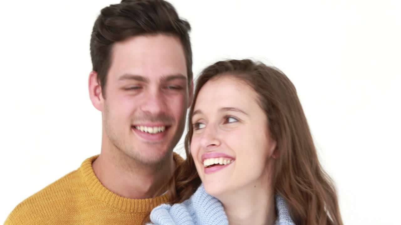 una pareja de jóvenes sonrientes abrazándose.