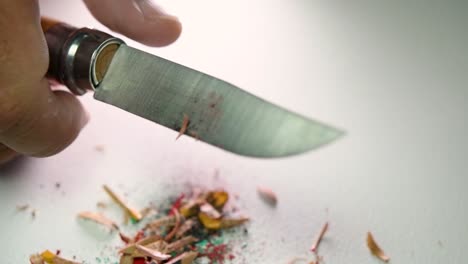 Footage-of-hands-slowly-sharpening-a-pencil-and-some-coloured-pencils-with-a-sharp-knife