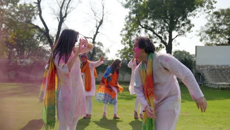 indian man throwing pink color at his wife in holi party