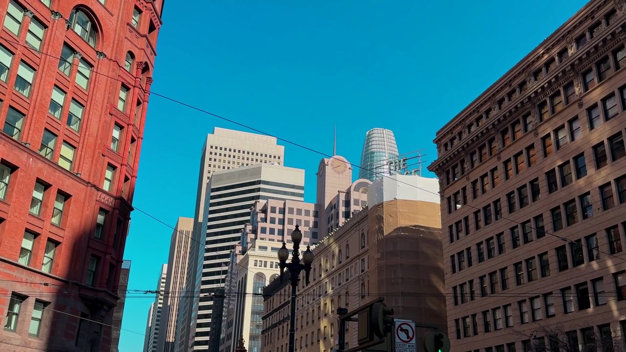 Vista dinâmica de rua da cidade com arranha-céus e arquitetura histórica sob céu azul claro