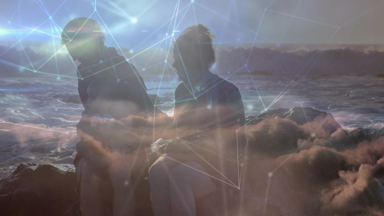 Vertical video: Shifting couple reacting to waves, talking on rocks with sun glare, digital overlay