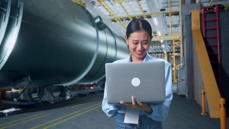 una mujer de negocios asiática usando una computadora portátil en una fábrica de fabricación de tubos