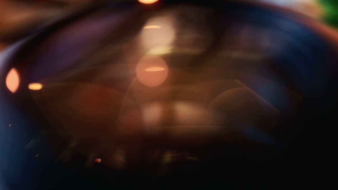 Close up of a camera lens showing curved glass elements and internal reflections