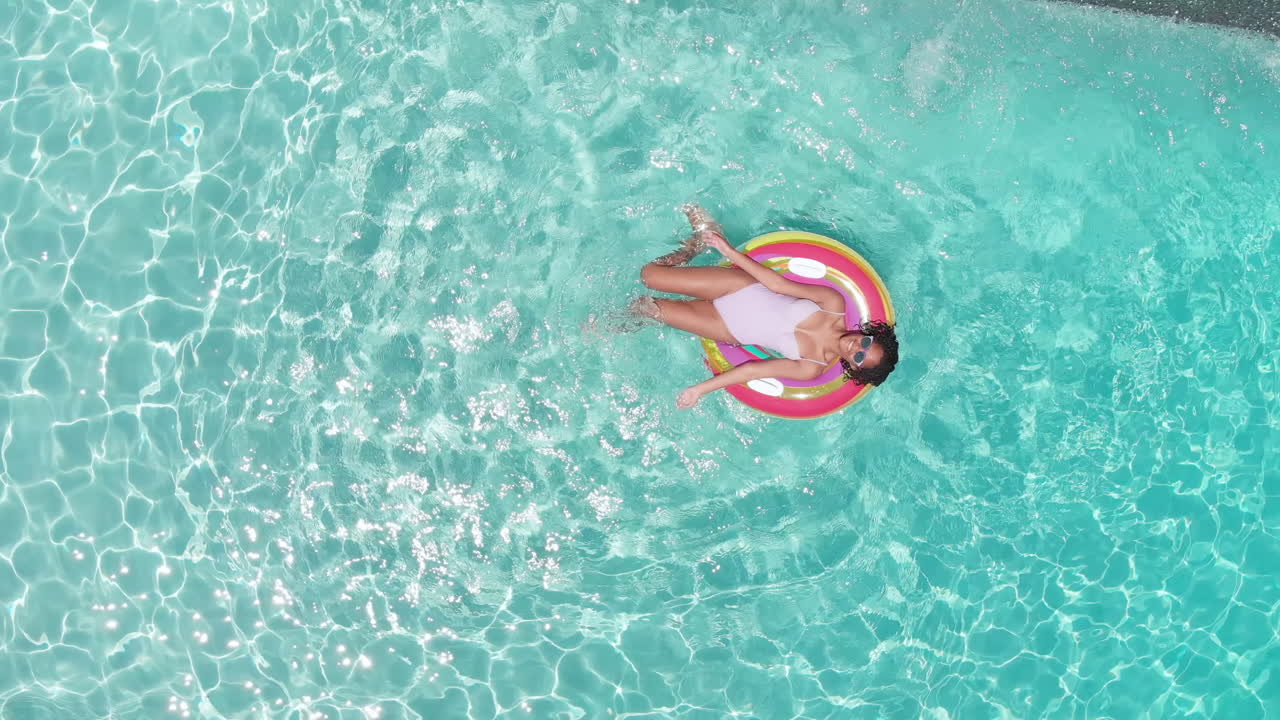 aerial de una adolescente afroamericana feliz jugando en un inflable en una piscina soleada, copia del espacio