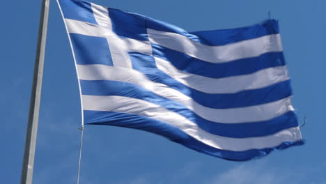 close up of a greek flag on flagpole waving rapidly in strong winds