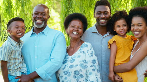 portrait of multi-generation family standing in garden smiling at camera