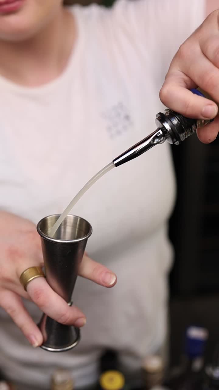 Bartender che versa liquido in un misurino per la preparazione di cocktail