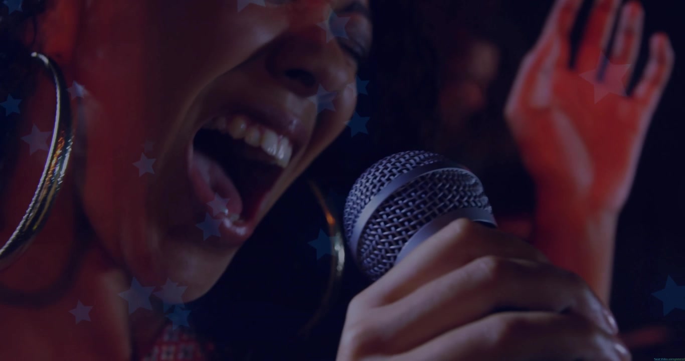 Vocalist bringing mic to lips singing, peaking then softening for music, animated star projections