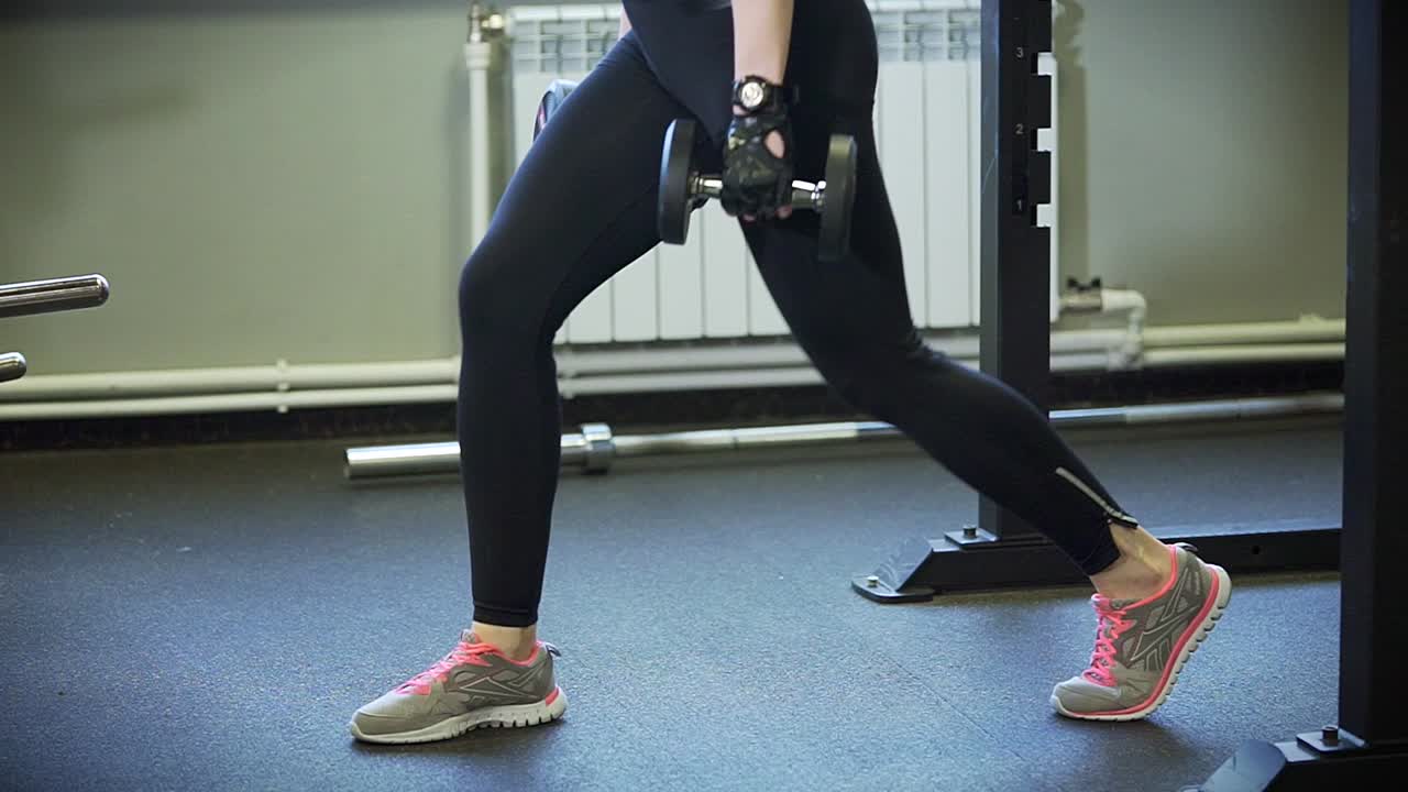 Woman Performing Dumbbell Lunges in Gym