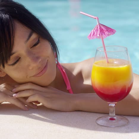 happy young woman eyeing a large tropical cocktail