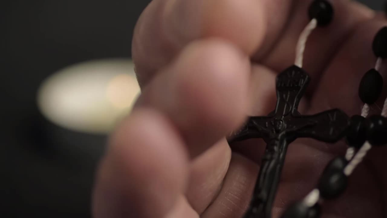 Hands opens to reveal string of rosary beads and crucifix