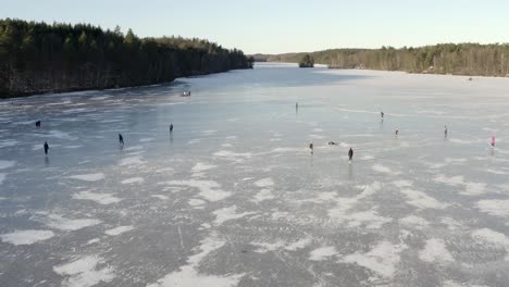 Un-Hermoso-Lago-Congelado-Con-Un-Grupo-De-Personas-Patinando-Sobre-Hielo-En-La-Brillante-Superficie-Sólida---Durante-El-Día