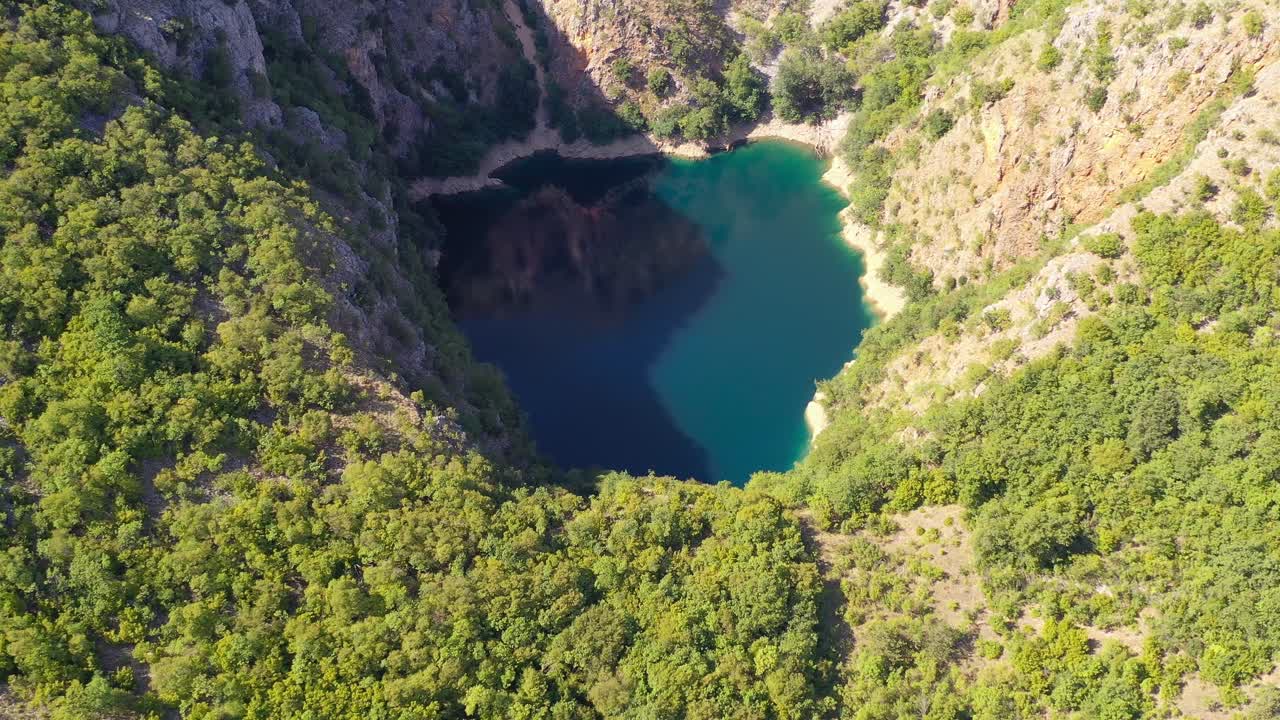 Blue Galjipovac Lake in Prolosko Blato marshes of Croatia inside the mountains, Aerial lowering view