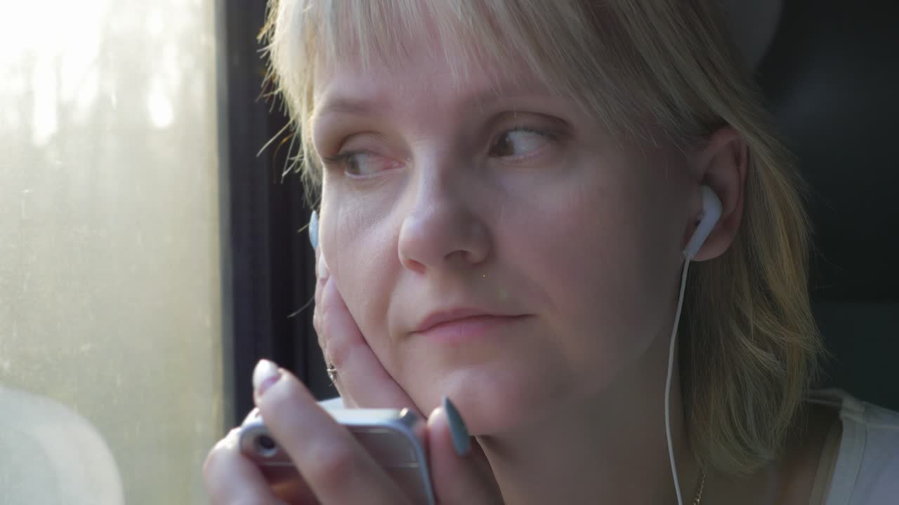 una mujer escucha música con auriculares mira por la ventana desde un viaje en tren y vacaciones
