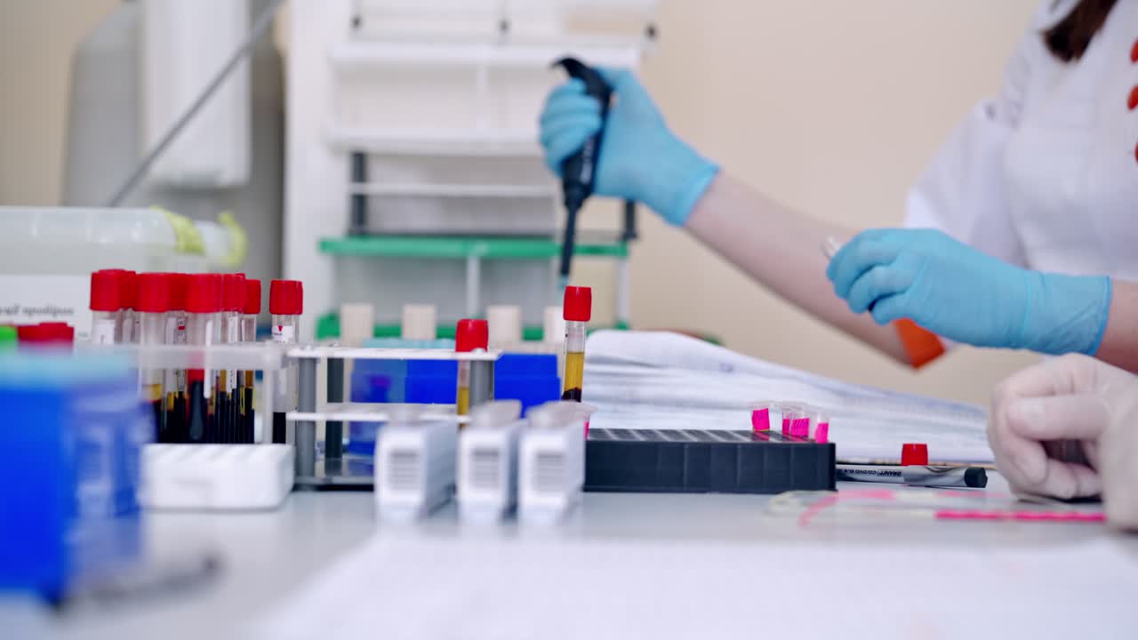 Lab technician holding blood tube sample for study. Medical technologist dropping blood into test tube in hospital laboratory