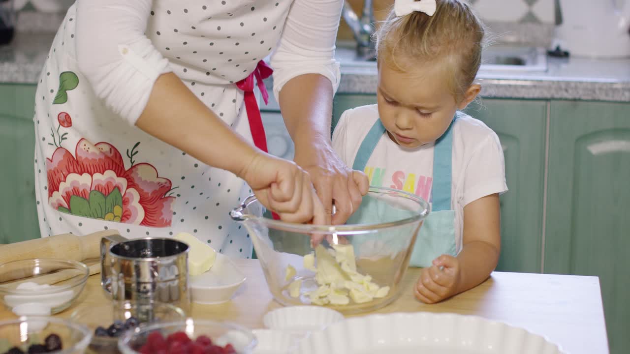 Mother teaching her small daughter to bake