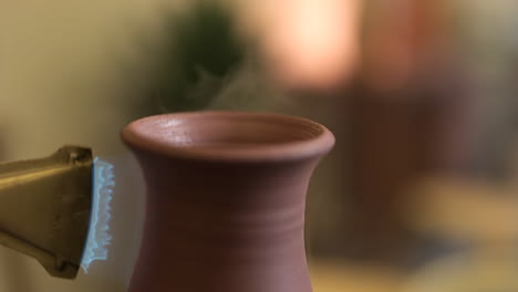 close up rotating clay vase on pottery wheel glazed with propane torch flame