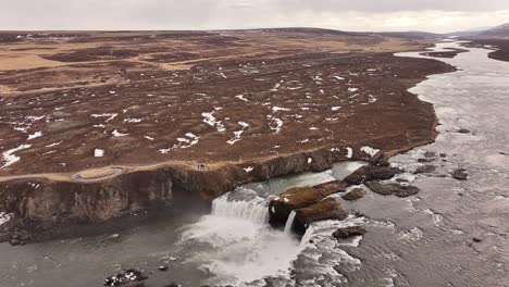 goðafoss pours over rocky cliffs in winter thaw near laugar iceland
