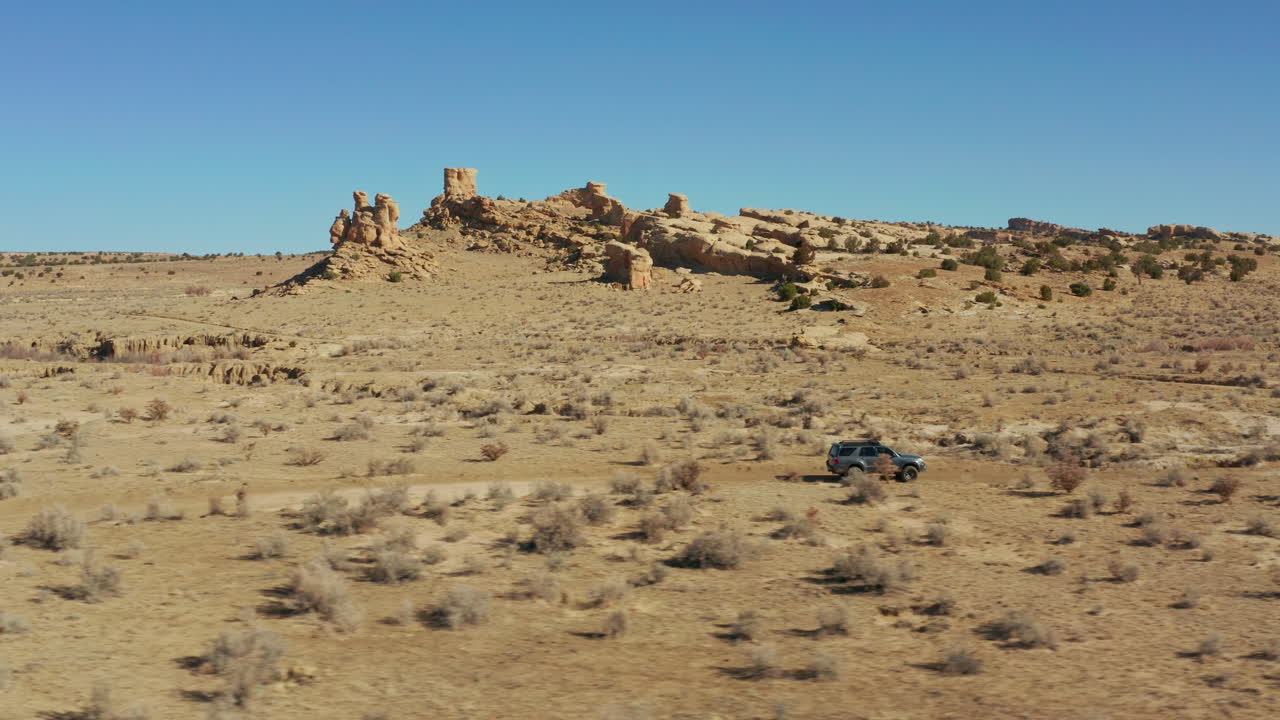 뒤에 암석이 있는 사막 비포장 도로에서 4x4 자동차로 공중 추적